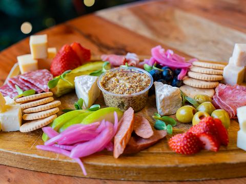 A grazing board of cured meats, cheeses, pickled vegetables, crackers and fresh fruit