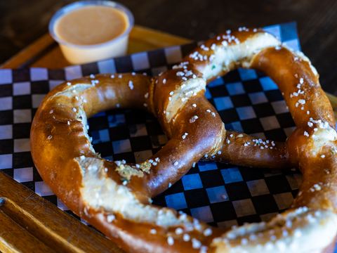 A large soft pretzel with coarse salt and a cup of warm beer cheese